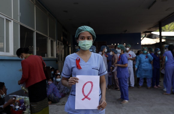미얀마 수도 양곤의 한 병원에서 한 여성 의료인이 3일 군부 쿠데타에 항의하는 의미인 붉은 리본이 그려진 플래카드를 들고 있다.-양곤 EPA 연합뉴스