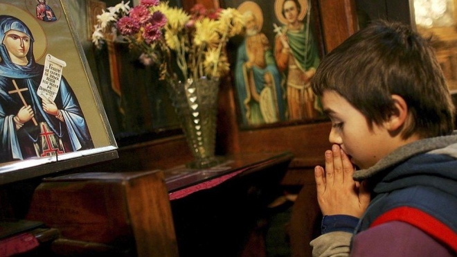 루마니아 정교회의 미사에 성실한 표정으로 기도를 올리는 한 아이. AFP 자료사진 연합뉴스