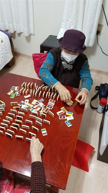서울 영등포구가 마련한 ‘집콕’ 아이템인 원목 만국기 도미노 세트를 대여한 한 할머니가 도미노를 세우고 있다. 영등포구 제공