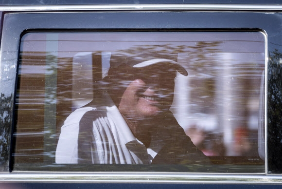 15일(현지시간) 미국 플로리다주 팜비치에서 차를 타고 가며 지지자들을 향해 웃는 도널드 트럼프 전 대통령. AP