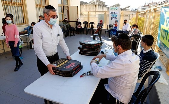 이스라엘 브네이브라크 접종소에서 코로나19 백신을 맞은 사람이 무료로 나눠주는 피자 한판을 챙겨가고 있다. AFP=연합뉴스