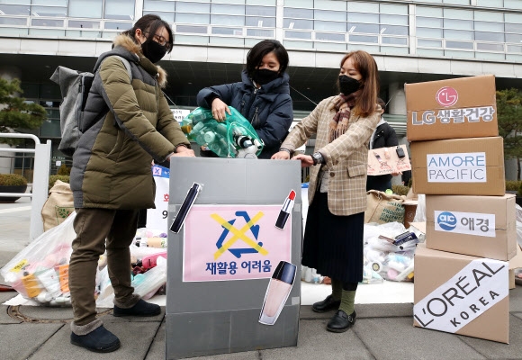 ‘화장품 어택 시민행동’ 활동가들이 25일 서울 종로구 LG생활건강 본사 앞에서 재활용이 어려운 화장품 용기들을 상자에 쏟아붓고 있다. 연합뉴스