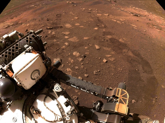 지난달 18일(이하 현지시간) 미국 항공우주국(NASA)의 탐사로버 퍼시비어런스가 지난 4일 처음으로 화성 표면을 돌아다니며 촬영한 사진이다. 위쪽의 타이어 자국이 뚜렷이 표면에 새겨져 있다. NASA/제트추진연구소(JPL) 캘리포니아 공과대학 제공 AP 연합뉴스 