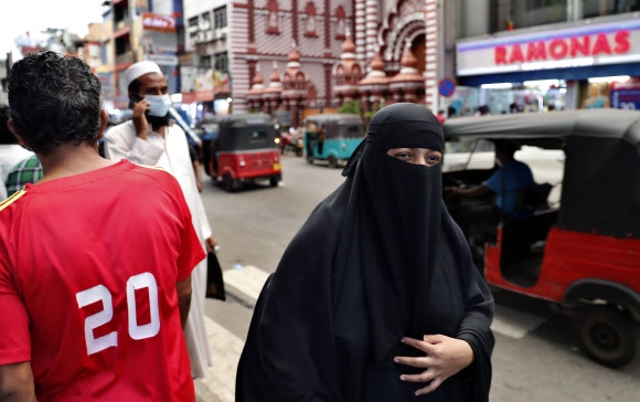부르카를 쓴 스리랑카 무슬림 여인이 13일(현지시간) 수도 콜롬버 거리를 걷고 있다. 이 나라 정부는 이날 부르카 착용을 금지하고 수천 곳의 이슬람 학교 마드라사를 폐쇄하기로 했다고 밝혀 파장이 일 것으로 보인다. 콜롬보 AP 연합뉴스 