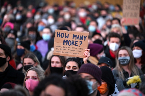 13일(현지시간) 영국 런던 남부 클래팜에서 열린 사라 에버라드 추모 집회에서 시민들이 “얼마나 더 많이 (죽어야 하나)”라고 적힌 피켓을 들고 있다. 클래팜 AFP 연합뉴스