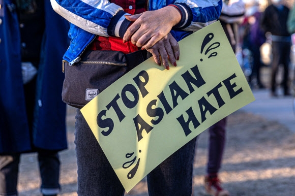 18일 미국 미네소타주 미네아폴리스에서 열린 아시안 연대 행진에서 한 참가자가 증오범죄를 멈추라는 팻말을 들고 있다.연합뉴스