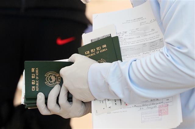 대한민국 축구 국가대표팀 스태프가 22일 오전 인천국제공항에서 일본으로 출국하는 선수들의 여권과 신종 코로나바이러스 감염증(코로나19) 검사 음성 확인서를 확인하고 있다. 2021.3.22 뉴스1