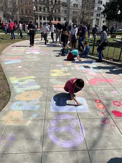 미국 워싱턴DC 맥퍼슨 스퀘어에서 21일(현지시간) 열린 ‘아시아계 미국인 혐오범죄’를 규탄하는 집회에 따라 나온 아이들이 ‘서로를 보호하자’(protect each other)라고 바닥에 분필로 쓴 글을 덧칠하며 놀고 있다.