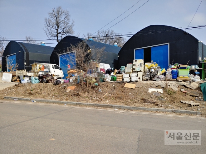 불법으로 하우스 건축물을 지어놓고 고물상을 잔뜩 쌓아놓고 있는 모습.