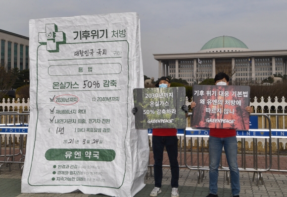 24일 서울 국회앞에서 열린 기후위기 처방전 담긴 초대형 약봉투 국회전달식에서 그린피스 회원들이 약봉투를 든 퍼포먼스를 펼치고 있다. 2021.3.24 박지환기자 popocar@seoul.co.kr