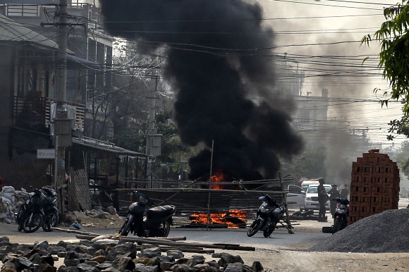 23일(현지시간) 미얀마 만달레이에서 군부 쿠데타 반대 시위 도중 경찰 오토바이가 불에 타며 검은 연기가 치솟고 있다. 만달레이 EPA 연합뉴스