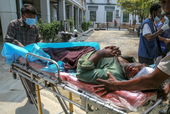 23일(현지시간) 미얀마 만달레이에서 군경의 총에 맞아 사망한 시민이 들것에 실려 옮겨지고 있다. 만달레이 AP 연합뉴스