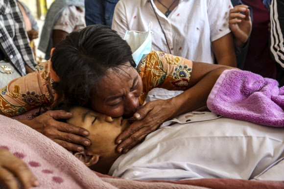 23일(현지시간) 미얀마 만달레이에서 군경의 총에 맞아 사망한 14살 소년 툰 툰 아웅의 장례식에서 가족들이 시신을 안고 눈물을 흘리고 있다. 만달레이 EPA 연합뉴스