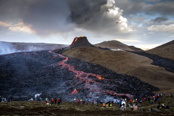 아이슬란드인들이 지난 19일(이하 현지시간) 밤부터 분출하기 시작한 레이캬비크 근처 파그라달스피아들 화산 분화구 근처를 23일 찾아 여전히 용암을 내뿜는 장관을 카메라에 담고 있다. 겔딩가달루르 AP 연합뉴스 