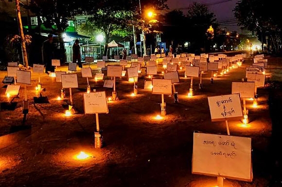 23일(현지시간) 미얀마 양곤의 한 거리에 촛불과 함께 군부 쿠데타를 규탄하는 팻말들이 세워져 있다. 쿠데타 항의 시위대를 상대로 한 군부의 유혈 진압으로 연일 사망자가 늘어가는 가운데 미얀마 시민들 사이에서는 각종 문구를 적은 팻말 등을 이용한 무인 시위가 확산하고 있다. 2021-03-24 양곤 AFP 연합뉴스