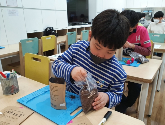 서울 중구 직영 돌봄교실에서 한 아이가 직접 꾸민 화분에 씨앗을 심고 있다. 중구 제공