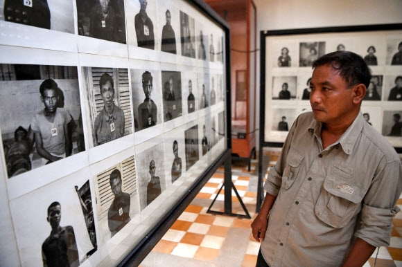 아일랜드 예술가 맷 러프레이가 왜곡해 캄보디아 국민들의 분노를 사고 있는 프놈펜의 투올 슬렝 대량학살 박물관(과거 S21 교도소)을 지난해 9월 2일 찾은 이곳 생존자 노릉 찬 팔이 희생자 사진들을 살펴보고 있다. AFP 자료사진 연합뉴스 