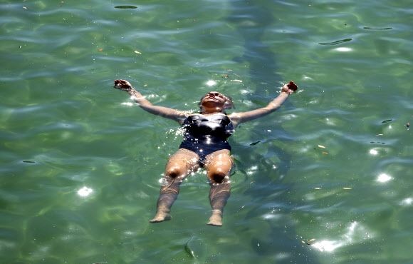 한 여성이 12일(현지시간) 호주 시드니 동부 교외 브론테 해변가 수영장에서 휴식을 취하고 있다. AP 연합뉴스