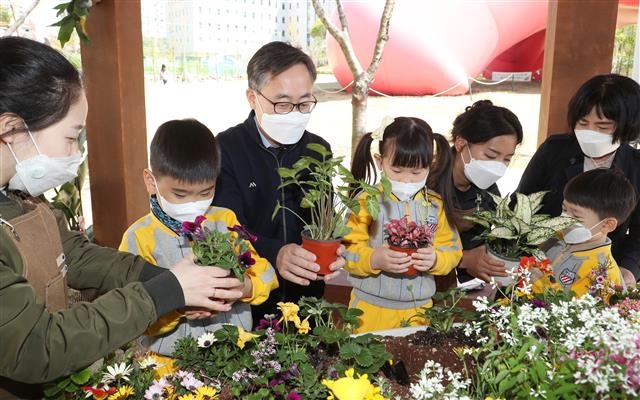 유성훈(왼쪽 세 번째) 금천구청장 지난 8일 서울 금천구 금나래중앙공원에서 열린 ‘봄날의 은행나무를 좋아하세요?’라는 가드닝 체험 프로그램에 참여해 어린이들과 함께 식물을 심고 있다. 금천구 제공