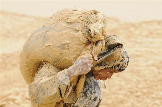 중국 장시성 난청현의 희토류 광산에서 한 남성이 진흙으로 뒤범벅이 된 짐을 어깨에 메고 힘겹게 옮기고 있다. 난청 로이터 연합뉴스 