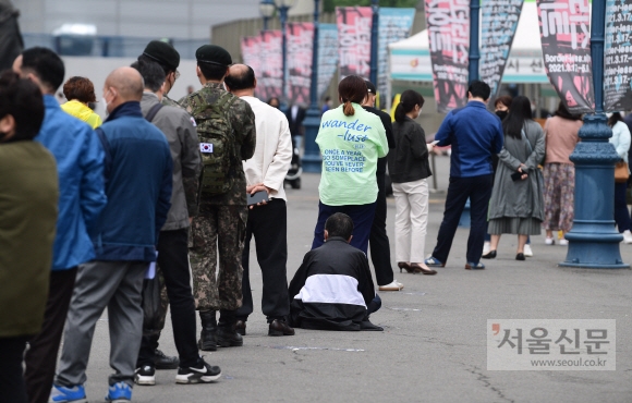 28일 서울역 광장에 마련된 코로나19 임시 선별검사소에서 한 시민이 검사를 기다리다 지쳐 땅에 주저 앉아있다.  2021. 4. 28 박윤슬 기자 seul@seoul.co.kr