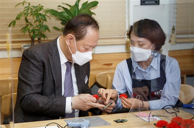 유동균(왼쪽) 서울 마포구청장이 지난 3일 노인일자리 전담기관인 마포시니어클럽의 ‘손끝공예’팀에서 일하는 어르신과 함께 카네이션을 만들고 있다. 마포구 제공