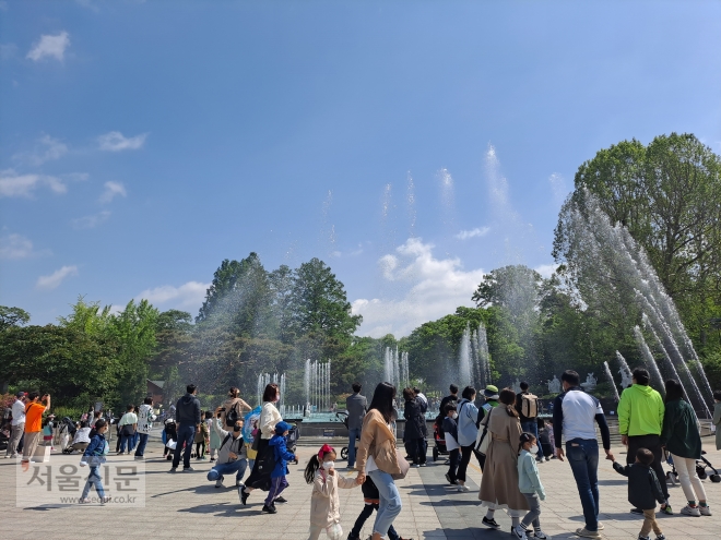 어린이날을 맞아 5일 서울 광진구 서울어린이대공원을 방문한 가족들이 분수대 앞을 지나거나 분수대를 배경으로 사진을 찍고 있다.