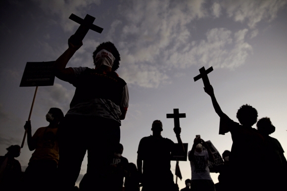 흑인 운동가들이  13일 리오데자네이로에서 열린 브라질 노예제도 폐지 133주년을 기념하는 인종차별 반대 집회에서 십자가를 들고  인종차별과 경찰 폭력에 항의하고 있다. 사진=AP 연합뉴스