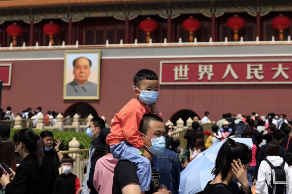 중국이 35년간 시행한 한 자녀 정책을 폐기하고 두 자녀를 인정한 지 6년 만에 산아제한을 더 완화해 세 자녀까지 허용하기로 했다. 사진은 지난 3일 베이징 톈안먼 광장에서 마스크를 쓴 한 남성이 아이를 목말을 태운 채 서 있는 모습. 베이징 AP 연합뉴스
