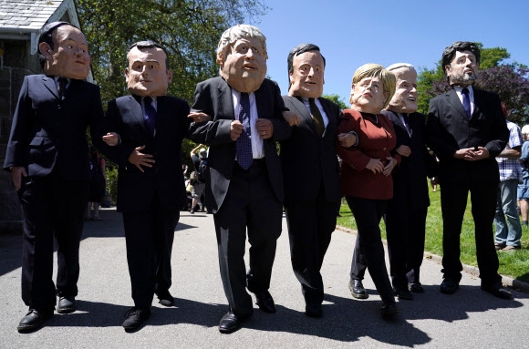 12일(현지시간) G7이 열리는 콘월에서 한 시민단체가 7개국 정상의 탈을 쓰고 행진하는 퍼포먼스를 하고 있다. AP