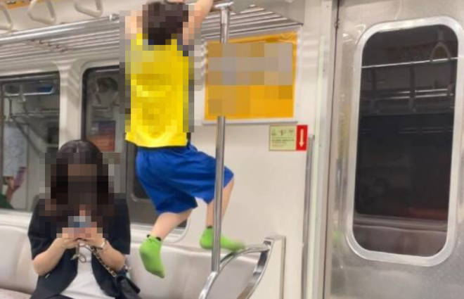 아이가 지하철 구조물을 놀이기구 삼아 노는 동안 보호자는 옆에서 핸드폰을 하고 있다. 사진=온라인 커뮤니티 보배드림 캡처