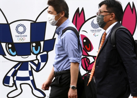 16일 일본 도쿄에서 마스크를 쓴 시민들이 도쿄올림픽 포스터 앞을 지나가고 있다. 도쿄 AP 연합뉴스
