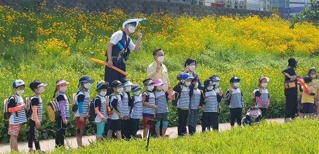 지난달 서울 금천구 안양천 일대 유채꽃 길에서 금천구청장과 인근 어린이집 아이들이 기념 촬영을 하고 있다. 금천구 제공