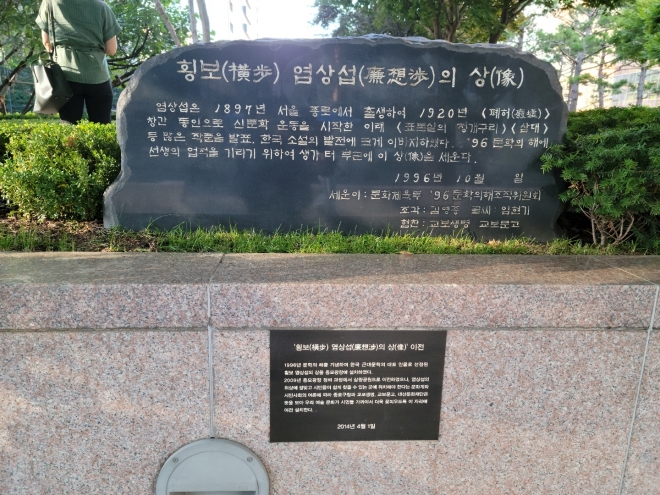 염상섭의 좌상을 세우게 된 배경을 설명하는 표지석과 현재의 자리로 좌상을 이전하게 된 경위를 소개하는 작은 안내판.
