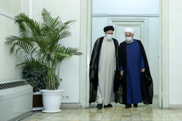 이란 13대 대선에서 승리한 강경보수 성향의 대법원장 세예드 에브라힘 라이시(왼쪽) 당선인이 19일(현지시간) 수도 테헤란에서 하산 로하니 대통령과 면담한 뒤 걸어 나오고 있다. 테헤란 AP 연합뉴스