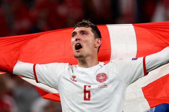 덴마크 대표팀의 수비수 안드레아스 크리스텐센이 22일(한국시간) 덴마크 코펜하겐 파르켄 스타디움에서 열린 유로 2020 조별리그 B조 최종 3차전에서 러시아를 4-1로 꺾은 뒤 국기를 펼쳐들고 기뻐하고 있다. 2연패 뒤 1승을 올린 덴마크는 극적으로 대회 16강에 합류했다. 코펜하겐 로이터 연합뉴스