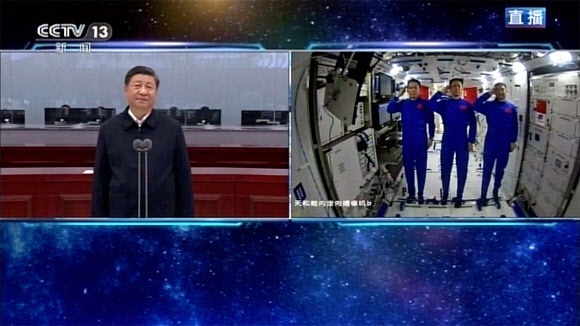 23일 시진핑(왼쪽) 중국 국가 주석이 우주정거장에 있는 중국 우주비행사들과 화상 통화를 하고 있다. 비행사들이 시 주석에게 거수경례를 하고 있다. 중국중앙(CC)TV 캡처 AP