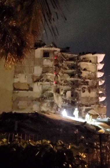 미국 플로리다주 소방요원들이 24일 마이애미 데이트 카운티의 12층 아파트 건물 일부가 무너져내려 처참한 몰골을 드러낸 가운데 구조 작업을 수행하고 있다. 인스타그램 캡처 로이터 연합뉴스 