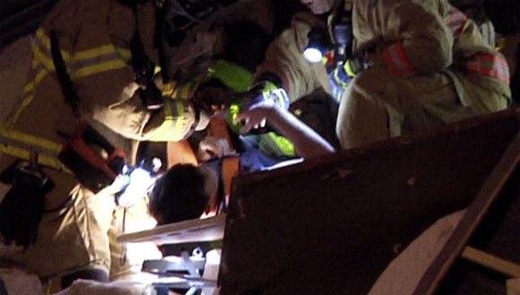 24일(현지시간) 미국 플로리다 서프사이드 건물 붕괴 현장에서 구조요원들이 한 소년을 구출하고 있다. AP