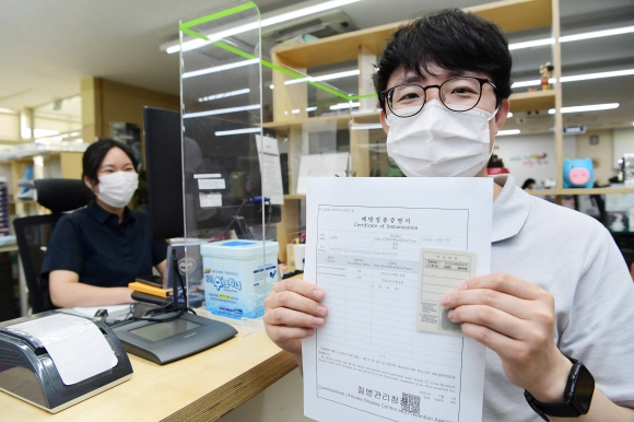 1일 서울 시내 한 주민센터에서 한 시민이 ‘백신 접종자 스티커’ 발급, 부착된 신분증과 종이증명서를 들고 있다. 정부는 이날부터 전국 주민센터에서 코로나 19 백신을 접종했음을 인증하는 ‘예방접종스티커’와 종이증명서를 발급 받을 수 있다고 밝혔다. 2021.7.1 오장환 기자 5zzang@seoul.co.kr