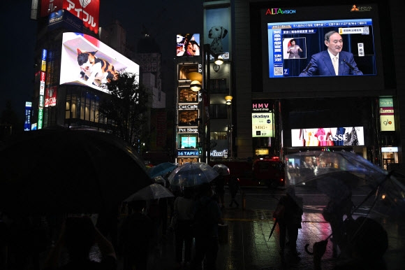 8일 저녁 스가 요시히데 일본 총리가 신종 코로나바이러스 감염증(코로나19) 긴급사태 관련 기자회견을 하는 모습이 도쿄 시내에 설치된 대형 스크린을 통해 생중계되고 있다. 2021-07-08 도쿄 AFP 연합뉴스