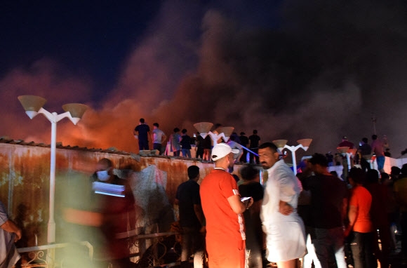 12일(현지시간) 이라크 남부 도시 나시리야의 코로나19 병원에서 화재가 발생해 시민들이 주위를 에워싸고 있다. 나시리야 AFP 연합뉴스