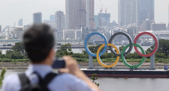 15일 도쿄 오다이바 인근에 설치된 오륜기 조형물을 한 시민이 촬영하고 있다.  도쿄 올림픽사진공동취재단