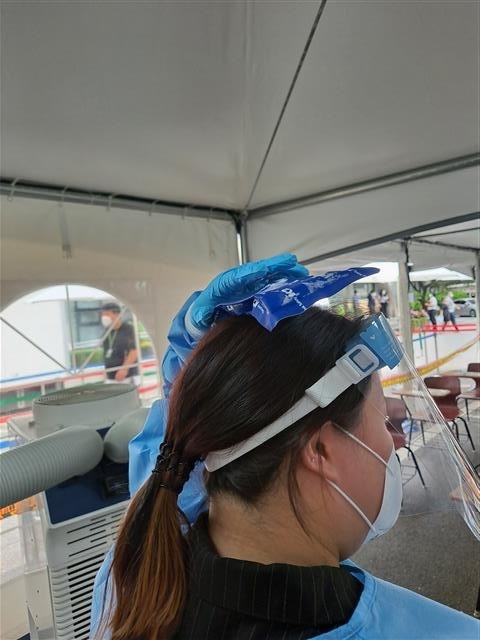 강남구 보건소 코로나19 선별검사소에서 근무자가 더위를 식히려 머리 위에 아이스팩을 얹고 있다.