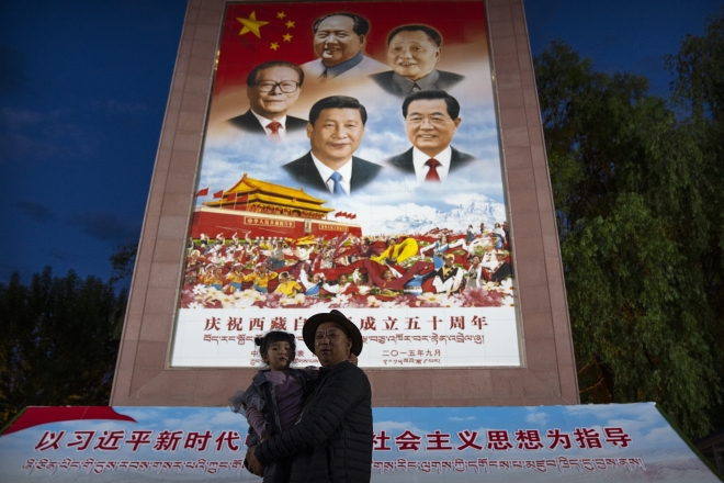 중국 서부 티베트 자치구 라싸의 포탈라궁 앞에 설치된 중국 지도자들 사진 앞에서 지난 6월에 한 남성이 소녀와 기념촬영을 하고 있다. 라싸 AP 연합뉴스