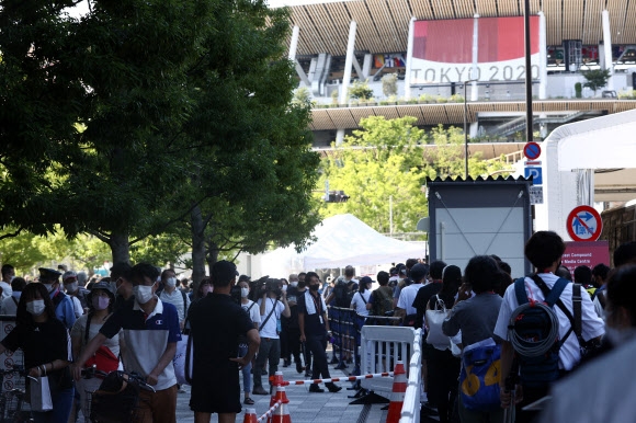 23일 도쿄올림픽 개회식이 열리는 도쿄 신주쿠 올림픽 스타디움 앞에 경기장에 입장하려는 대회 관계자들(오른쪽)과 일본 시민들(왼쪽)이 뒤섞여 있다. 연합뉴스