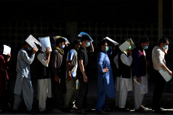 지난 25일 카불에 있는 오피스에서 여권 신청서를 제출하려고 사람들이 줄을 서고 있다. 미군 철수 결정 이후 매일 새벽 수십 명이 오피스가 열리기도 전에 줄을 선다.  AFP 연합뉴스