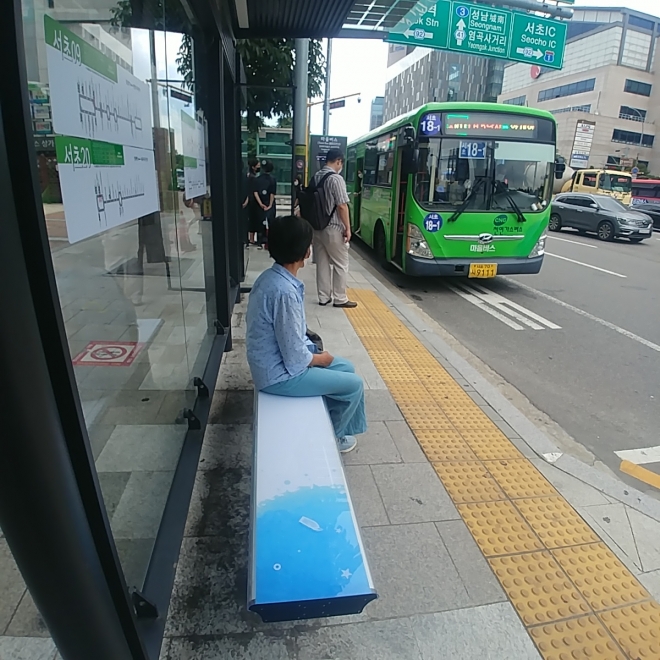 한 주민이 서울 서초구 버스정류장에 설치된‘서리풀 쿨링의자’에 앉아 버스를 기다리고 있다. 서초구 제공 