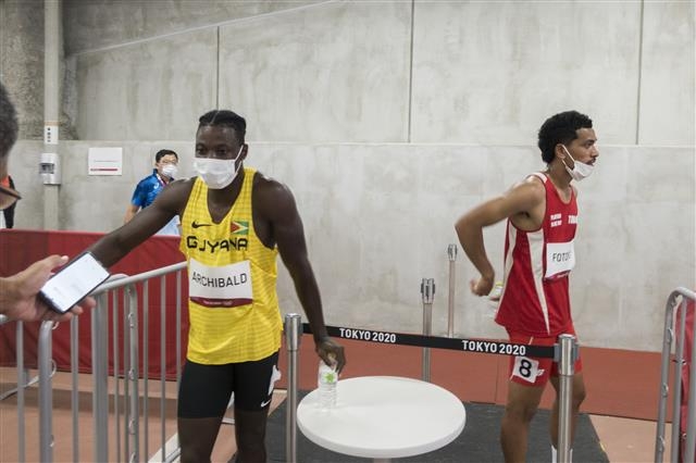 도쿄올림픽 육상 남자 100m 자격예선에 출전한 에마뉘엘 아치볼드(왼쪽·가이아나)가 지난달 31일 도쿄올림픽 주경기장에서 경기 후 믹스트존에서 취재진과 인터뷰하는 중에 로널드 포토필리(통가)가 인터뷰 없이 빠져나가고 있다.