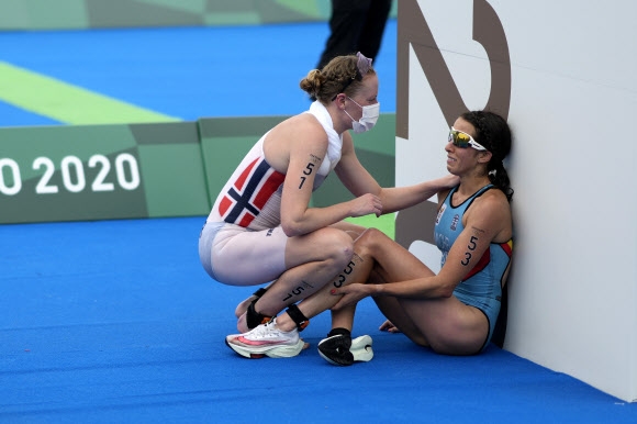 지난달 27일 일본 도쿄 올림픽 여자 트라이애슬론 경기에서 24위로 달리던 로테 밀러(노르웨이)가 바닥에 주저앉아 울고 있는 클레르 미셸(벨기에)에게 응원의 말을 건네고 있다. AP